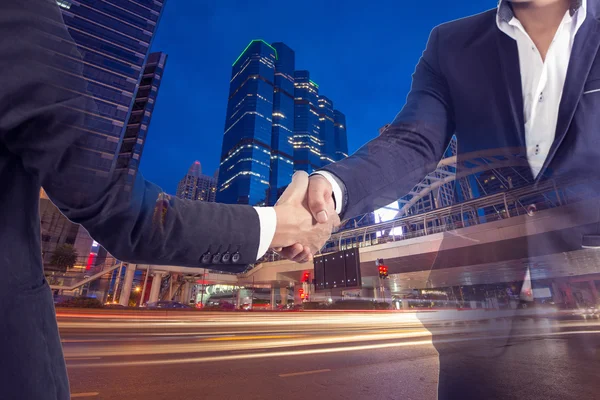 Two businessman shaking hands on modern city background