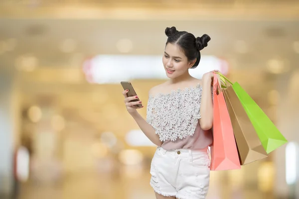 Attractive shopper woman holding shopping bags with smart phone