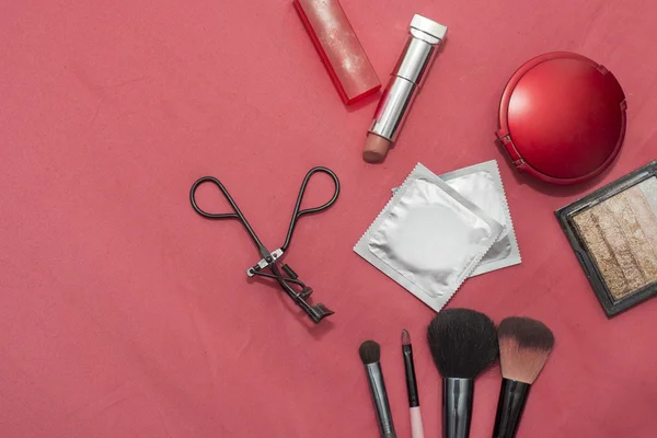 Set of cosmetics, contraceptives, condom on red background