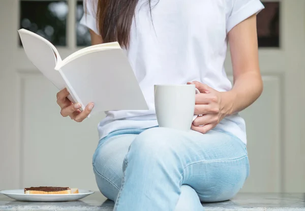 Asian woman sitting on marble chair in front of house for have breakfast and read a book in the morning