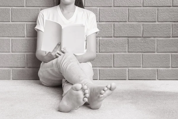 Woman sitting at the corner of house for reading a white book in free time in the afternoon , relax time of asian woman in black and white tone