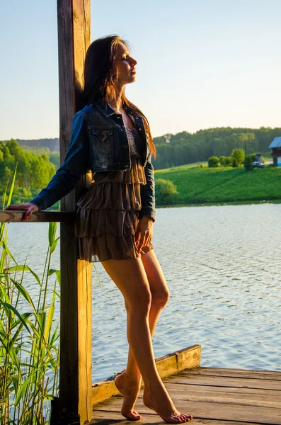 Girl standing on a wooden pier .