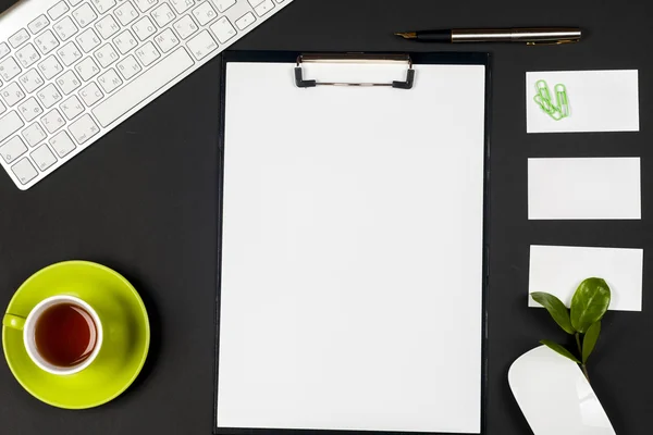 Office black desk table with white computer, business card blank, flower, coffee cup and pen.