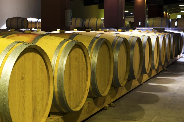 Row of barrels with red wine leak in a Bulgarian winery. Selective focus