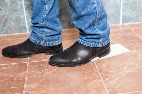 Toilet paper stuck to the sole of a dress shoe