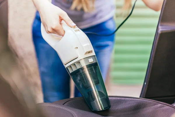 Woman Cleaning Interior Of Car Using Vacuum Cleaner