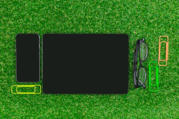 Blank notebook, phone on  green grass