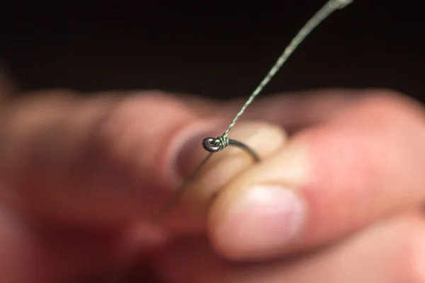 Man hand tying a fishing hook. Tie the KD rig.  Selective focus. Tie Hook Close Up. Tie Fishing Hook  Tying a fishing hook Process. Tie the KD rig and catch more carp.