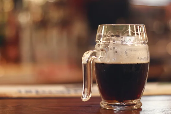 Black beer on wooden table. Half mug Black beer.
