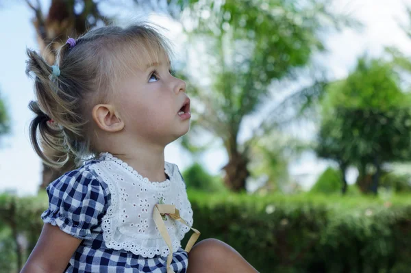 Cute little girl looking at the sky in summer day