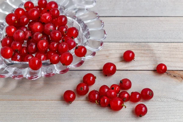 Organic garden berries on old wood table, from above. red currant. crystal vase in the shape of heart.