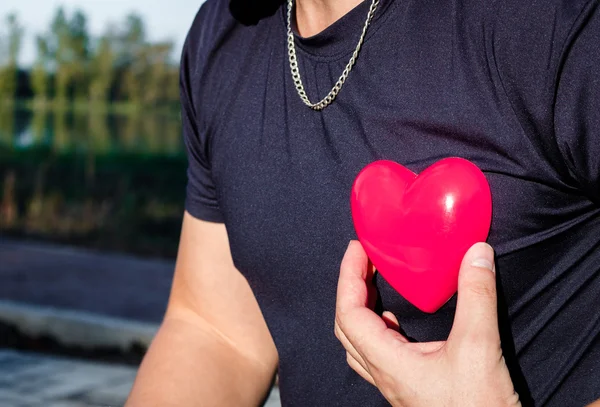 Man holding a red plastic heart.