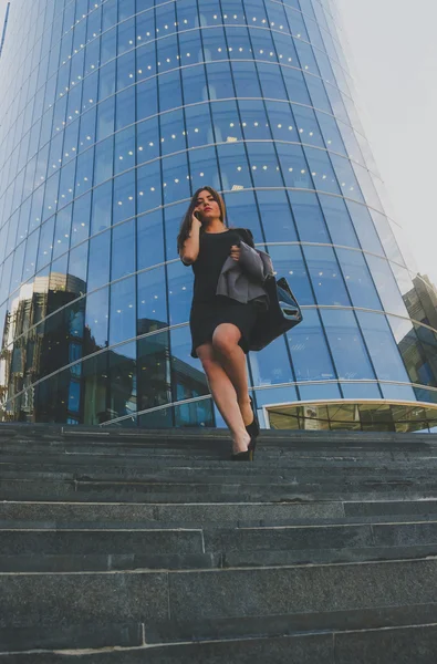Beautiful girl in black jacket in his hands coming down the steps of the business center