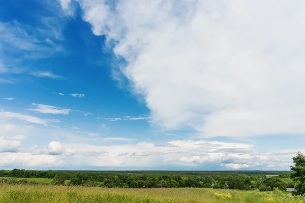 Countryside natural background. Rural path winds along the field. Cloudscape in sunny day. Russia.