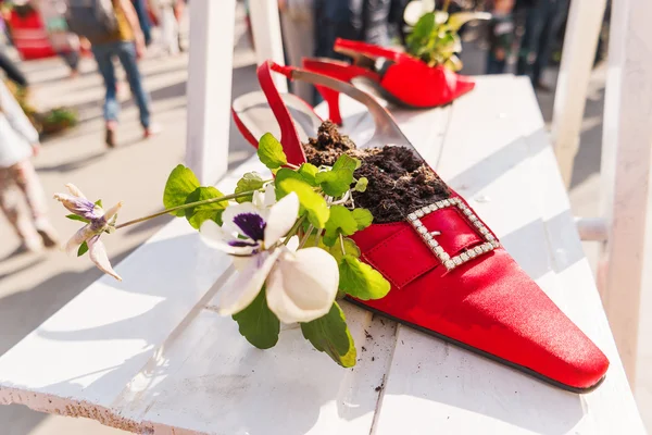 Funny street decorations - painted old boots with plants and flowers inside.
