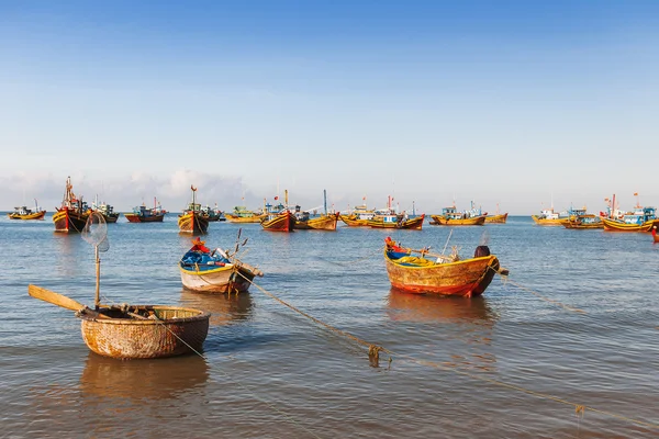 Fishing village, market and colorful traditional fishing boats near Mui Ne, Binh Thuan, Vietnam. Early morning, fishermen float to the coast with a catch.