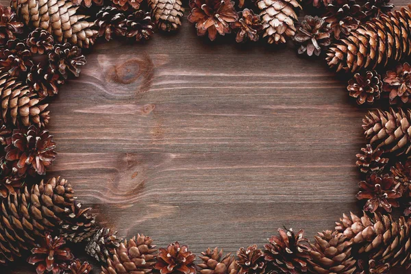 Frame of pine cones on wooden background. Place for your text. Mock up.