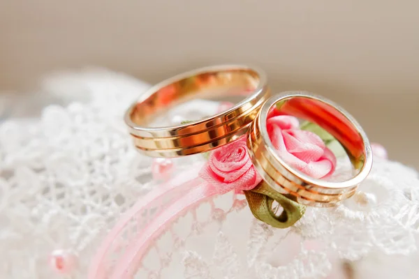 Golden wedding rings on lace white fabric. Wedding embroidery detail.