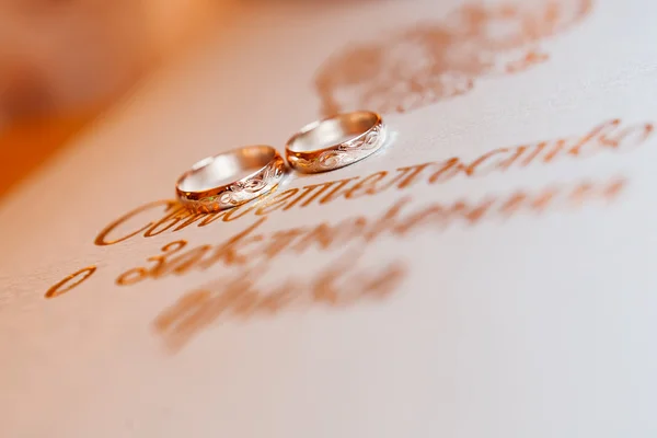 Golden wedding rings on background with golden monogram.
