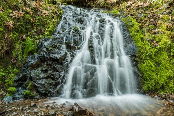 Small wide waterfall with mossy rocks and smooth water