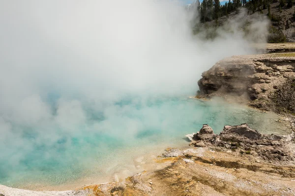 Light blue pool of Excelsior geyser with steam rising from hot spring in Midway basin