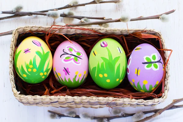 Painted Easter eggs in a wicker box on a white background.