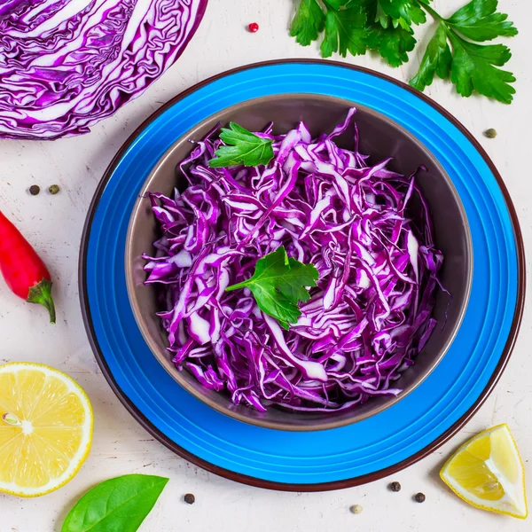 Purple cabbage salad and ingredients on a bright background.