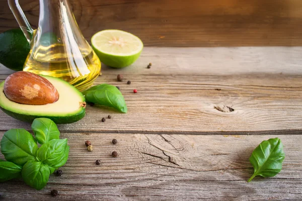 Food background with avocado, lime, olive oil and basil on old