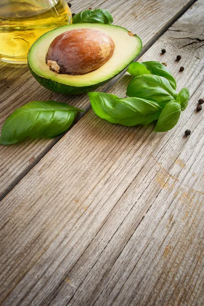Food background with avocado, olive oil and basil on old weather