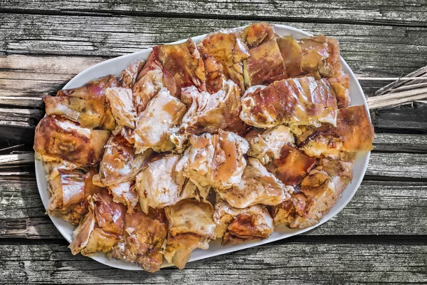 Plateful of Spit Roasted Pork Slices On Old Wooden Picnic Table