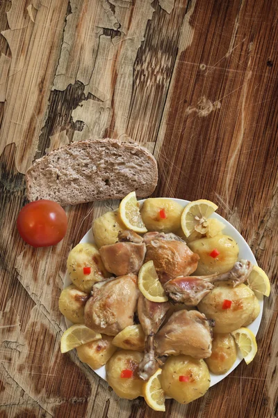 Plate of Fried Chicken Legs with Potato and Lemon Slices Bread and Tomato on Old Wooden Table