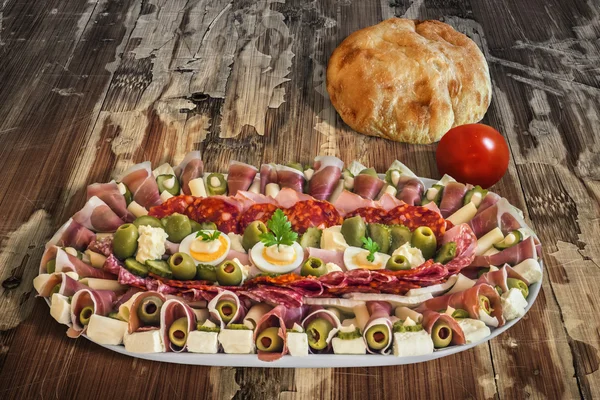 Plateful of Serbian Appetizer Meze with Pita Bread and Tomato on very old Wooden Table