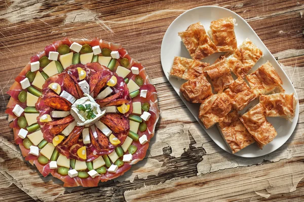 Plateful of Savory Appetizer Meze with Cheese Pie Gibanica Slices on Oblong Platter Placed on Old Wooden Backdrop