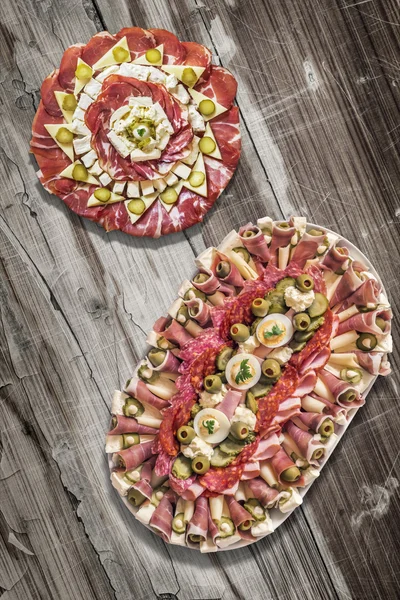 Two Platters of Savory Antipasto Meze Appetizers on Old Cracked Peeled Wooden Table