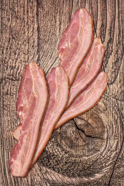 Pork Bacon Rashers on Old Knotted Cracked Wood Background