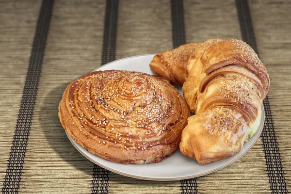 Croissant Puff Pastry Snail Rolls Sprinkled with Sesame Seeds on Parchment Plated Place Mat