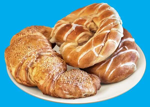 Plate of Pretzels and Croissant Puff Pastry Sprinkled with Sesame Seeds, Isolated on Blue Background