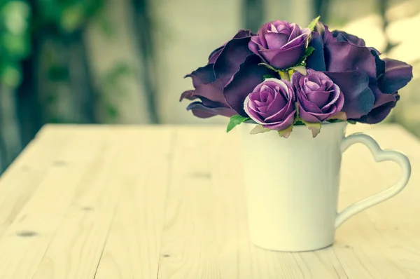 Purple artificial rose in cup heart shape handle for love.