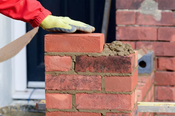 Bricklayer laying brick on wall