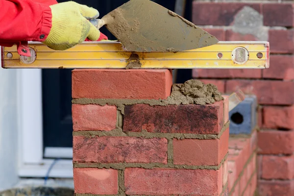 Bricklayer laying brick on wall and checking it is level