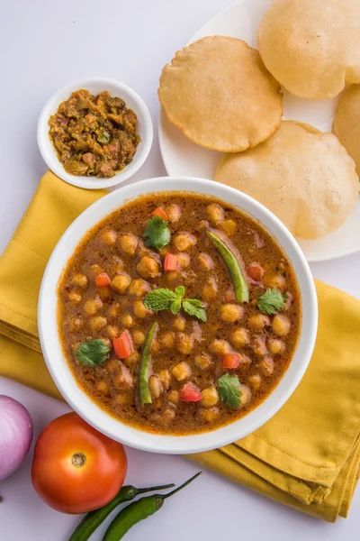 Spicy chick peas also known as Chola Masala or Chana Masala or Chole served with fried puri, pickle and green salad