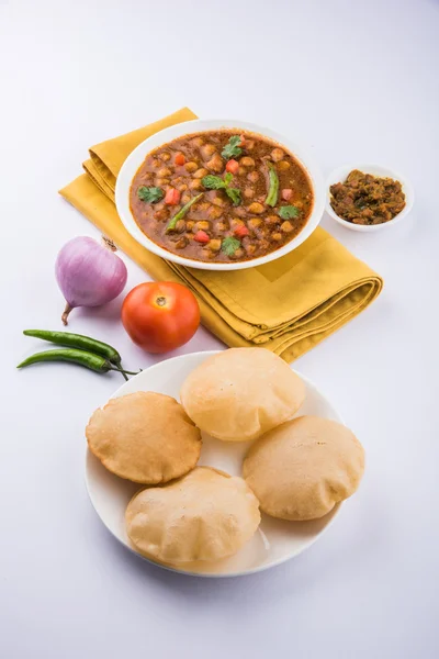 Spicy chick peas also known as Chola Masala or Chana Masala or Chole served with fried puri, pickle and green salad