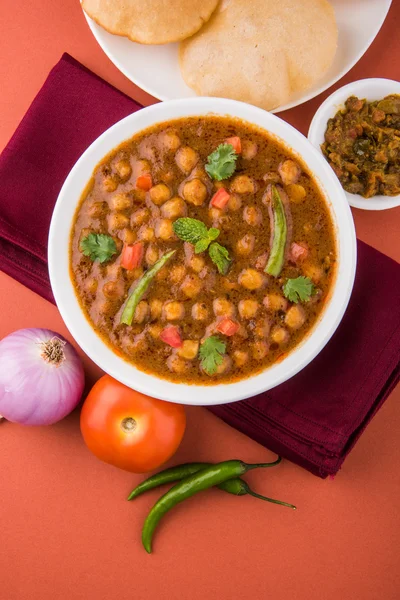 Spicy chick peas also known as Chola Masala or Chana Masala or Chole served with fried puri, pickle and green salad