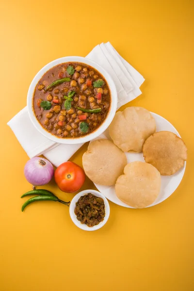 Spicy chick peas also known as Chola Masala or Chana Masala or Chole served with fried puri, pickle and green salad