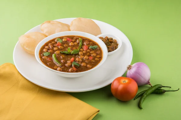 Spicy chick peas also known as Chola Masala or Chana Masala or Chole served with fried puri, pickle and green salad