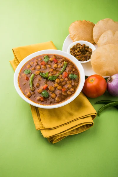 Spicy chick peas also known as Chola Masala or Chana Masala or Chole served with fried puri, pickle and green salad