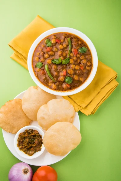 Spicy chick peas also known as Chola Masala or Chana Masala or Chole served with fried puri, pickle and green salad