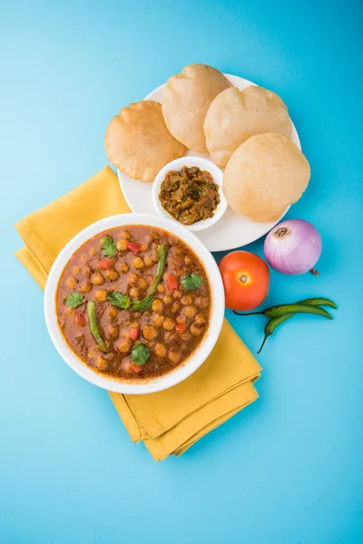 Spicy chick peas also known as Chola Masala or Chana Masala or Chole served with fried puri, pickle and green salad