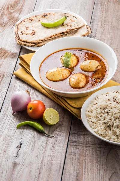 Egg curry with roti/chapati and jeera rice, tasty and spicy anda curry with roti and rice, indian egg masala curry served in ceramic bowl with roti, salad and jeera rice