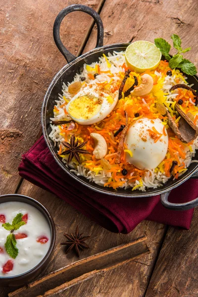 Basmati rice slowly cooked with Masala roasted egg and spices served in kadhai or kadai with yogurt dip, selective focus, egg biryani or anda rice or egg rice